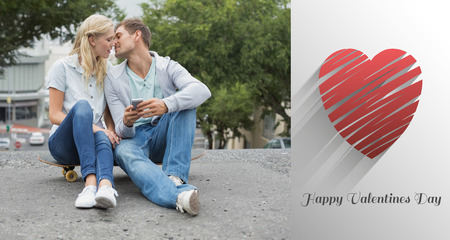 Hip young couple sitting on skateboard kissing against cute valentines message