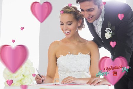 Happy young couple signing wedding register against cute valentines messageの写真素材