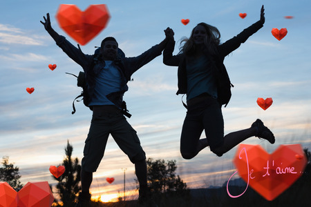 Silhouette couple jumping against the sky against valentines love heartsの写真素材