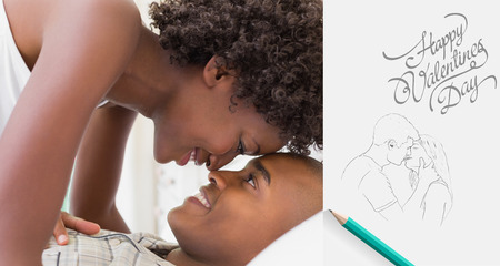 Intimate couple messing about in the morning on bed against cute valentines messageの写真素材