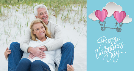 Romantic senior couple relaxing at beach against cute valentines messageの写真素材