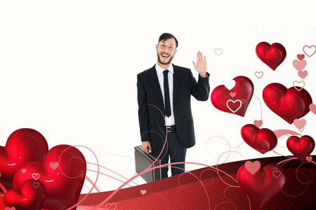 Geeky businessman waving at camera against valentines heart designの写真素材