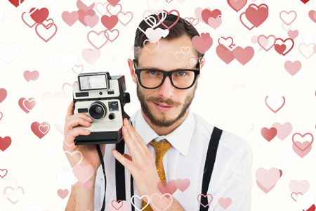 Geeky hipster holding a retro camera against valentines heart designの写真素材