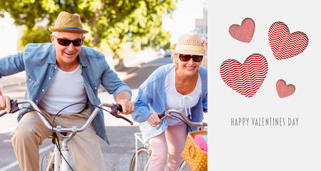Happy mature couple going for a bike ride in the city against cute valentines messageの写真素材