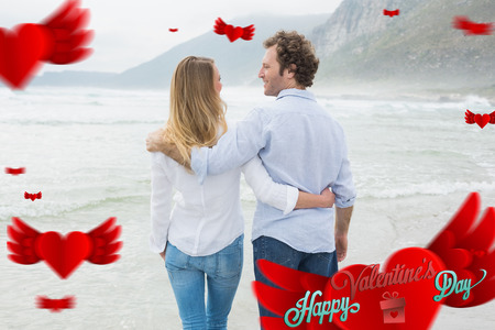 Rear view of a romantic couple at beach against happy valentines dayの写真素材