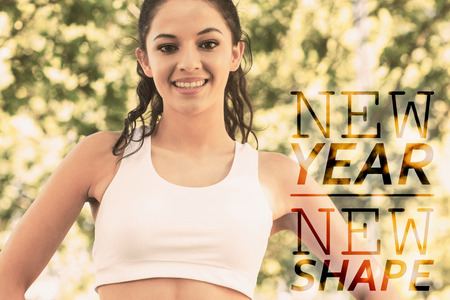 Active cheerful brunette standing hands on hips smiling against new year new shapeの写真素材