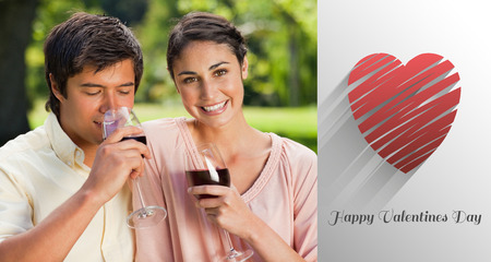 Woman smiling while her friend is drinking wine against cute valentines messageの写真素材
