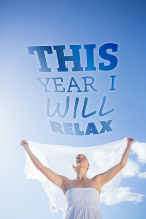 Pretty blonde in white dress holding up shawl on the beach  against this year i will relaxの写真素材
