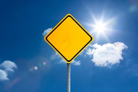 yellow sign against bright blue sky with cloudsの写真素材