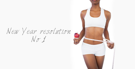Woman holding apple and measuring her waist on white backgroundの写真素材