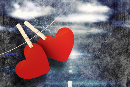 Hearts hanging on line against stormy sky over road with lightningの写真素材