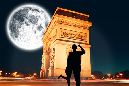 Attractive couple smiling and cheering against large moon over arc de triomphの写真素材