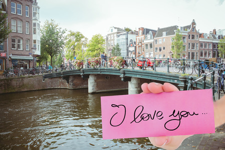 Young woman holding blank card against canal in amsterdamの写真素材