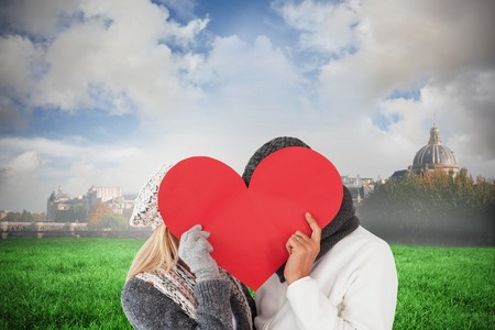 Couple in winter fashion posing with heart shape against paris under cloudy skyの写真素材