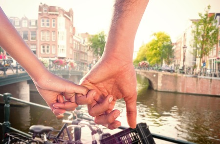 Loving young couple holding hands against canal in amsterdamの写真素材