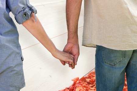 Couple holding hands in park against autumn leaves against white woodの写真素材