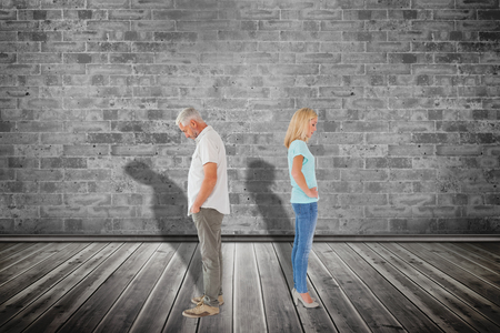 Unhappy couple not speaking to each other  against grey roomの写真素材