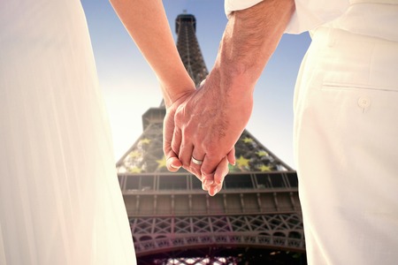 Bride and groom holding hands close up against eiffel towerの写真素材