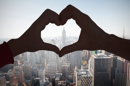 Couple making heart shape with hands against new yorkの写真素材
