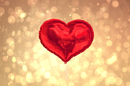 Red heart balloon against yellow abstract light spot designの写真素材