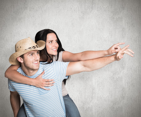 Man giving his pretty girlfriend a piggy back against weathered surfaceの写真素材