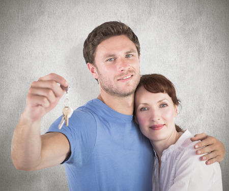 Couple holding keys to home against weathered surfaceの写真素材