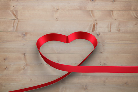 Red ribbon heart against bleached wooden planks backgroundの写真素材