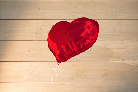 Red heart balloon against bleached wooden planks backgroundの写真素材