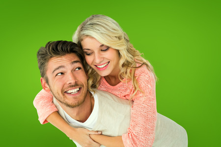 Handsome man giving piggy back to his girlfriend against green vignetteの写真素材