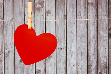 Heart hanging on line against digitally generated grey wooden planksの写真素材