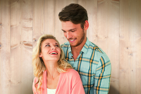 Attractive young couple embracing and smiling against wooden planksの写真素材