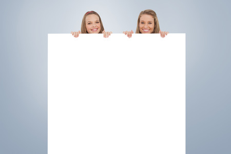 Close up of young women behind a blank sign against grey vignetteの写真素材
