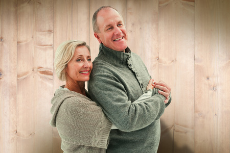 Happy mature couple in winter clothes against wooden planksの写真素材