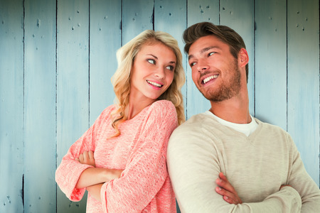 Attractive couple smiling with arms crossed against wooden planksの写真素材
