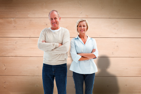 Happy mature couple smiling at camera against overhead of wooden planksの写真素材