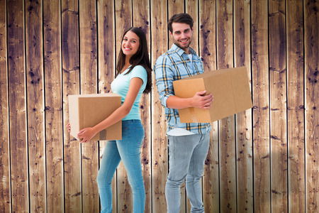 Happy young couple with moving boxes against wooden planks backgroundの写真素材
