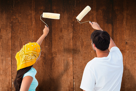 Happy young couple painting together against weathered oak floor boards backgroundの写真素材
