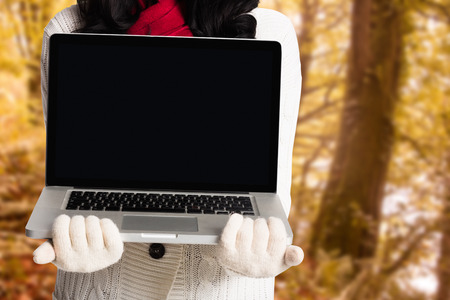 Woman holding a laptop computer against tranquil autumn scene in forest