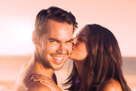 Attractive woman on the beach kissing her boyfriend on the cheekの写真素材