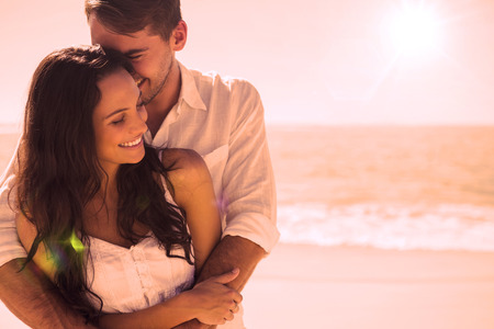 Attractive couple cuddling at the beachの写真素材