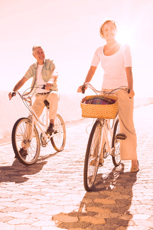 Happy senior couple going for a bike ride on a sunny dayの写真素材