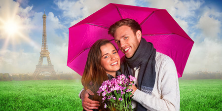 Cheerful young couple with flowers and umbrella against eiffel towerの写真素材