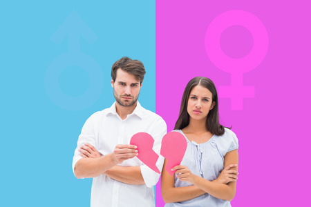 Upset couple holding two halves of broken heart against pink and blue