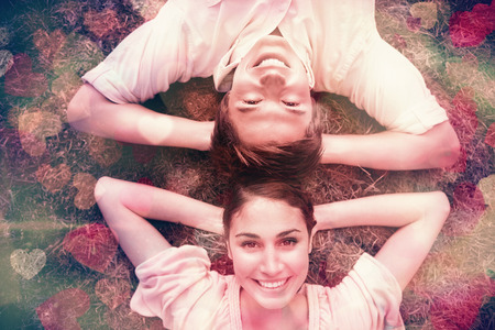 Man and a woman smiling while lying head to head with both of their arms resting behind their neck on the grassの写真素材