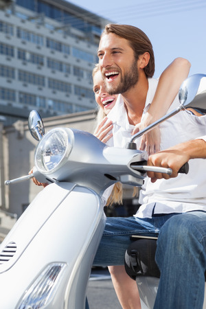 Cute couple riding a scooter on a sunny day in the cityの写真素材