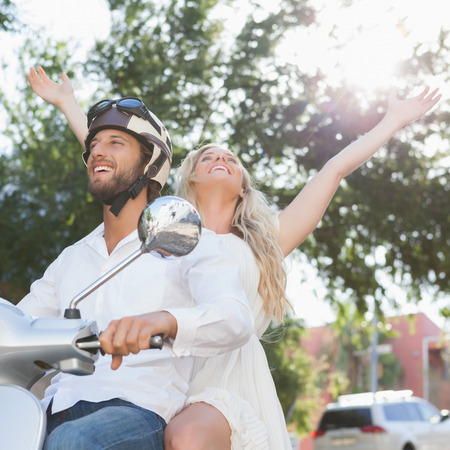 Cute couple riding a scooter on a sunny day in the cityの写真素材