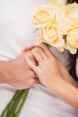 Close up of young man giving girlfriend white roses at home in the kitchenの写真素材