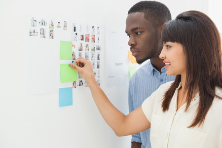 Teamwork standing and taking sticky notes in the officeの写真素材