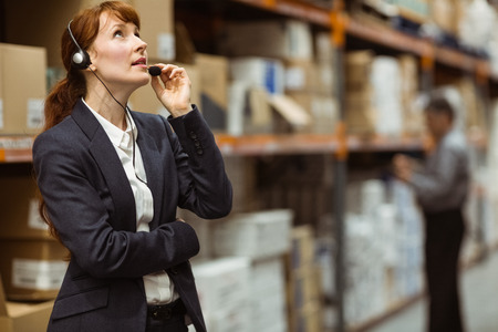 Elegant manager talking into a headset in a large warehouseの写真素材