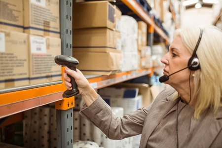 Manager with headset scanning package in a large warehouseの写真素材